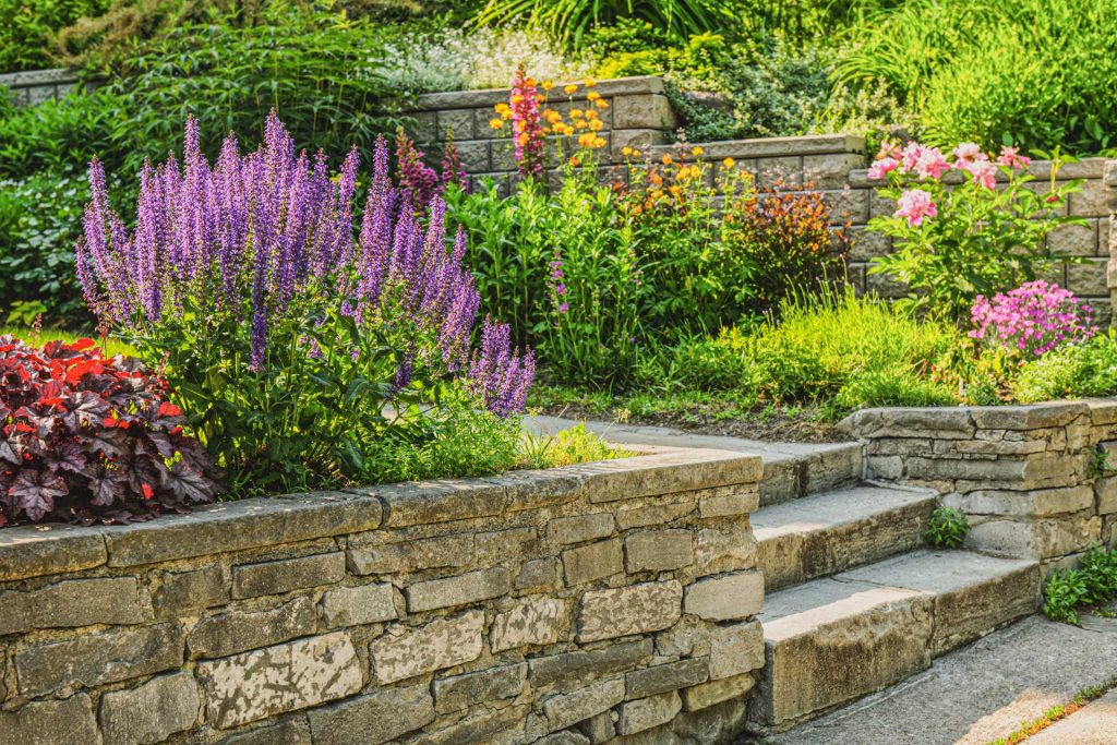 Natural stone landscaping in home garden with steps and flowerbeds